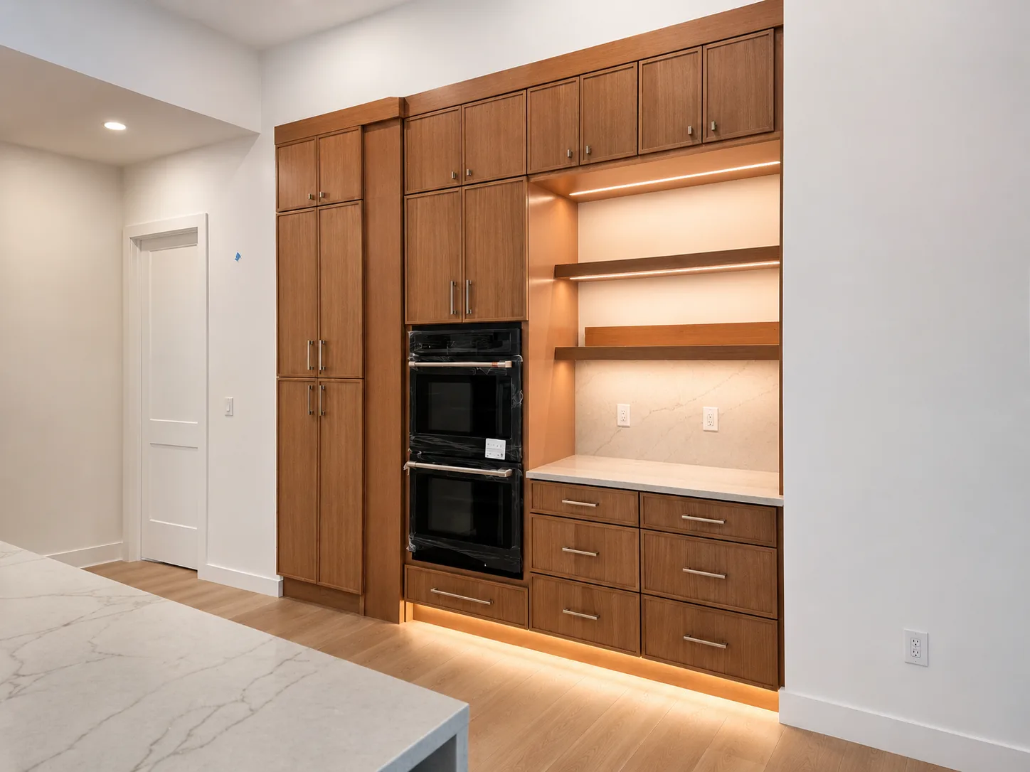 Finished Sarasota kitchen wood cabinet wall with appliance storage, shelving, backsplash, hardware, and warm lighting
