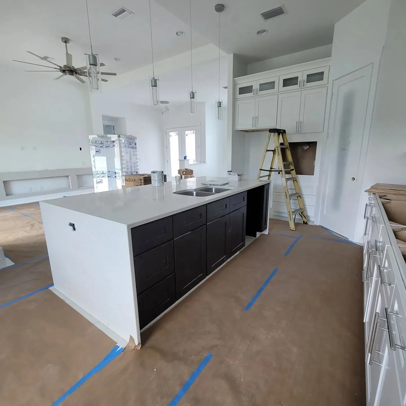 Venice-area kitchen remodel progress with black island cabinets, white perimeter cabinets, countertop, and lighting