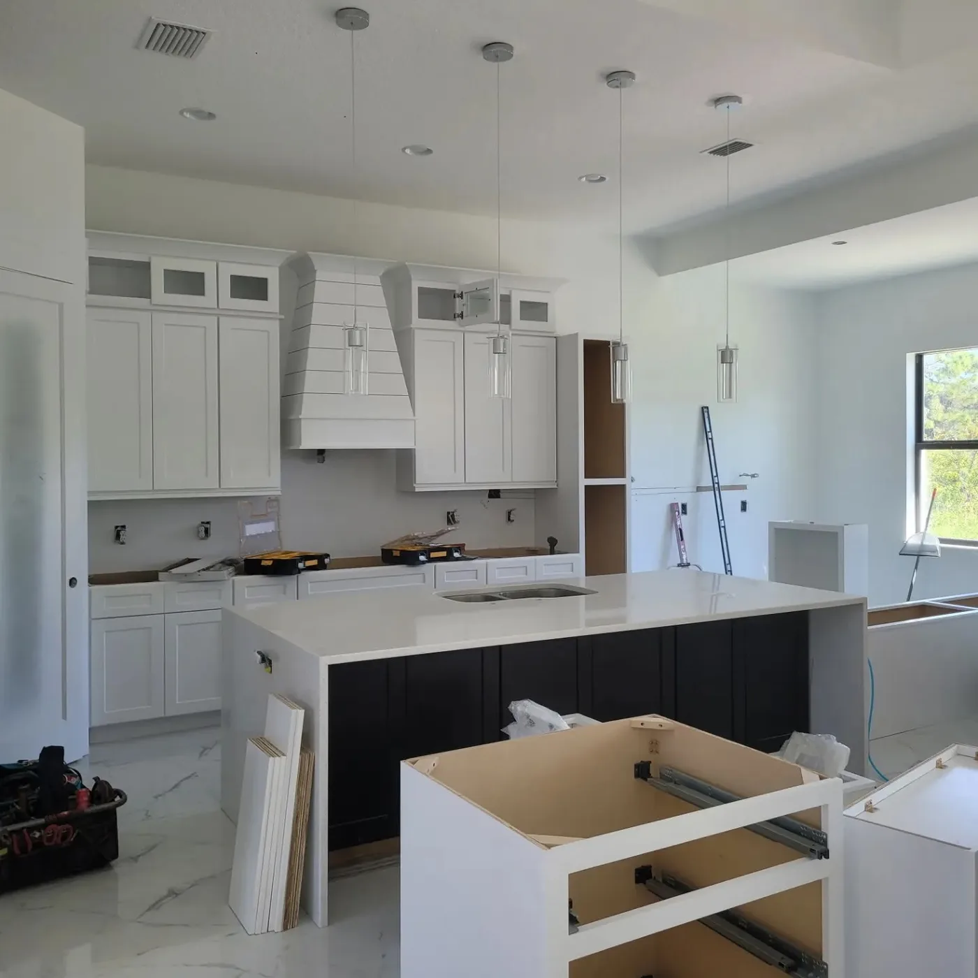 Venice-area kitchen remodel progress with white hood surround, white cabinets, black island, countertop, and pendant lighting